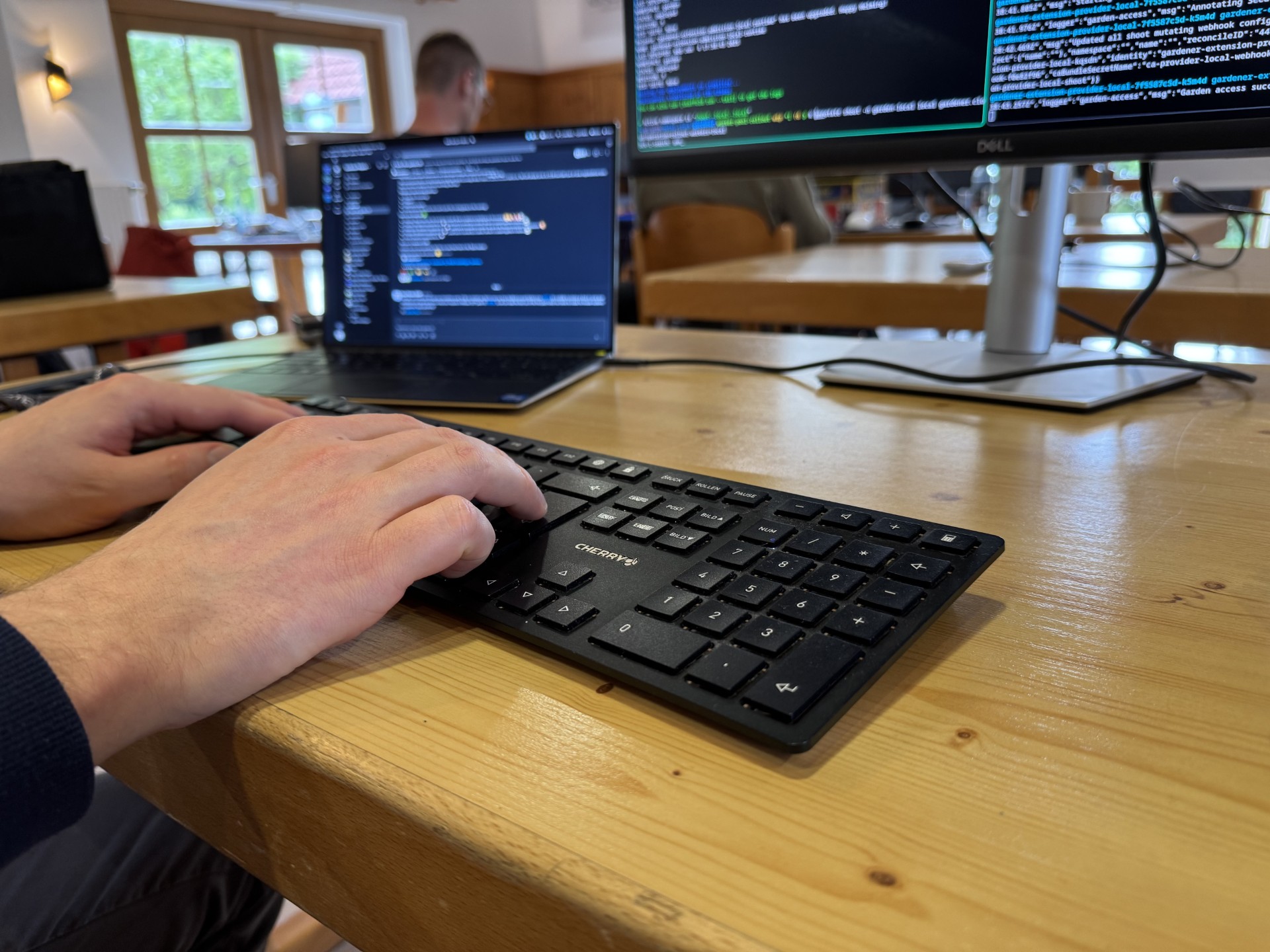 Typing on the keyboard with laptops and screens in the background